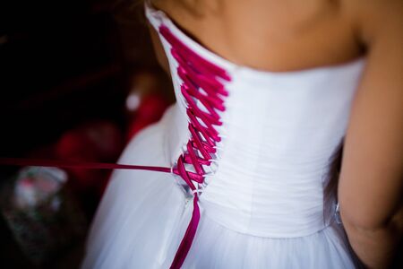 Bride from the back. Lacing the wedding dress.