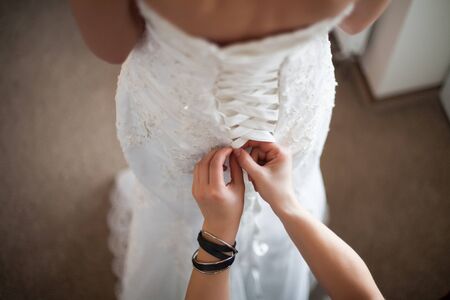 Bride from the back. Lacing the wedding dress.の写真素材