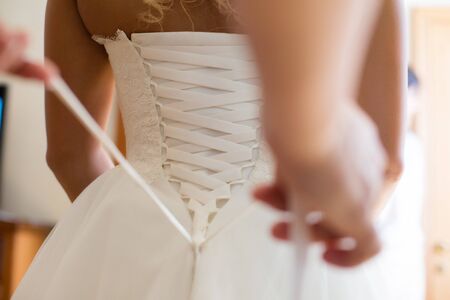 Bride from the back. Lacing the wedding dress.の写真素材