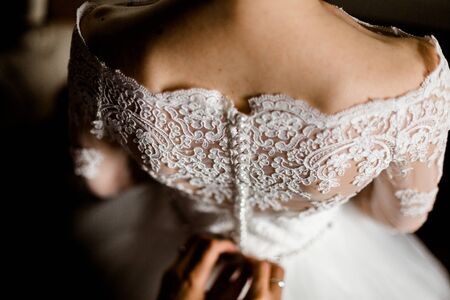 Bride from the back. Bridesmaid zips the wedding dress.の写真素材
