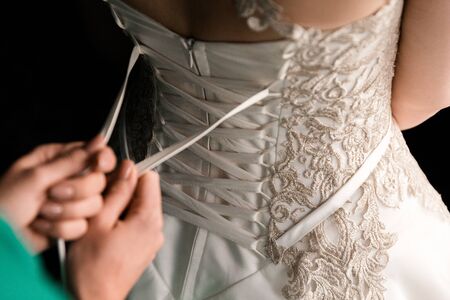 Bride from the back. Lacing the wedding dress.の写真素材