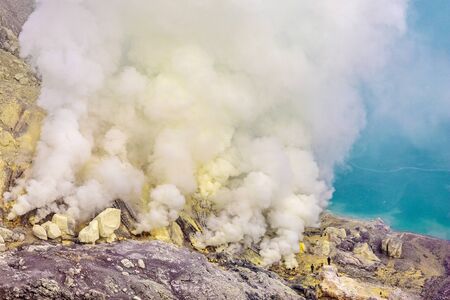 Crater of a volcano with a green sulfuric volcanic lake and volcanic smoke. View of the smoking volcano Kawah Ijen in Indonesiaの写真素材