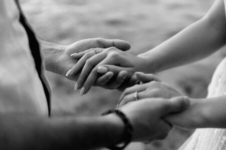 Young couple holding hands.Man holds in his hands the hands of a girl on the background of water, closeup photoの写真素材