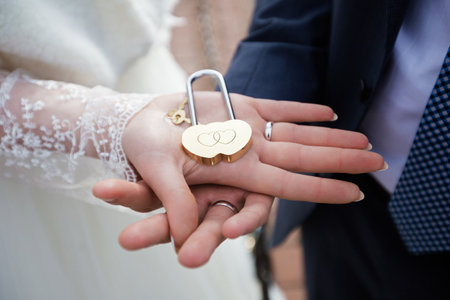 Bride and Groom Holding a Heart-shaped Padlock Symbolizing Unionの写真素材