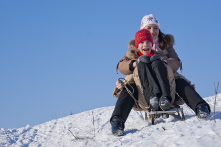 Two happy sisters sledding at winter timeの写真素材