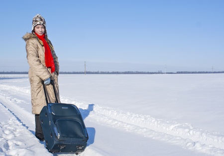 Teen girl with a suitcase outdoors at winter timeの写真素材