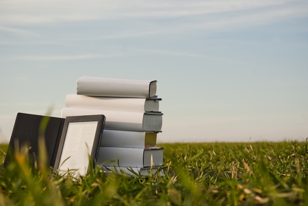 Stack of books with ebook reader outdoors laying on grassの写真素材