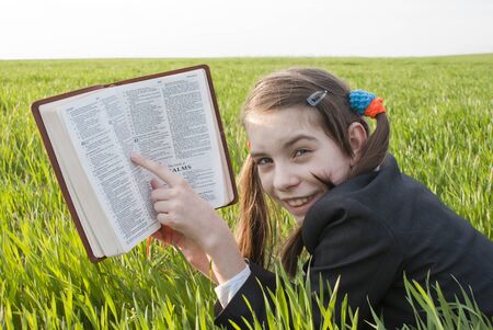 Girl with the Bible laying on the grassの写真素材