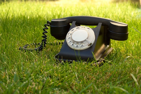 Retro styled rotary telephone in the grassの写真素材