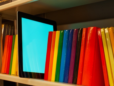 Row of colorful books and electronic book reader on the shelfの写真素材
