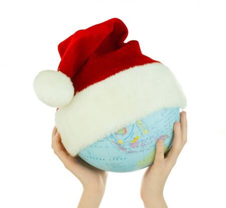 Hands holds globe with Santa's hat over white backgroundの写真素材