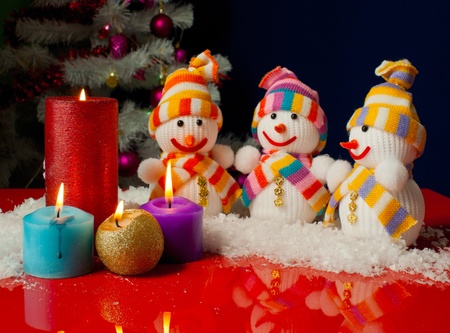 Three snowmen and burning candles over the blue backgroundの写真素材