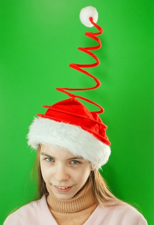 Pretty Santa girl, closeup portrait of a teen girl wearing Christmas hat against green backgroundの写真素材