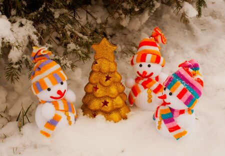 Three snowmen with golden evergreen tree staying outdoorsの写真素材