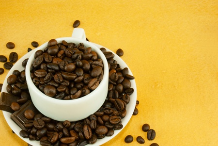 Cup full with coffee beans on yellow backgroundの写真素材