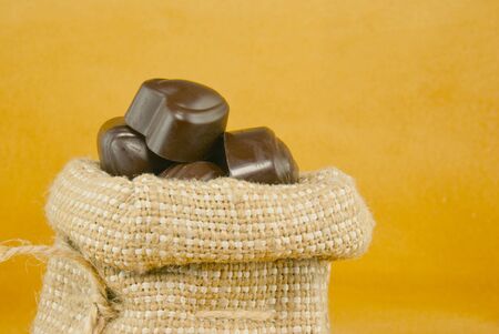 Close up of the sack full of chocolate candies over yellow backgroundの写真素材