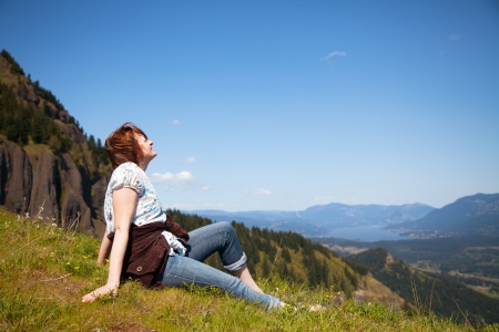Woman sits at the top of a cliff relaxingの写真素材