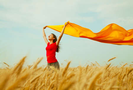Teen girl at a wheat field with yellow fabricの写真素材