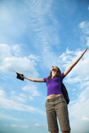 Young woman staying with raised hands against blue skyの写真素材