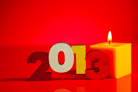 Wooden 2013 year number with a burning candle over red backgroundの写真素材