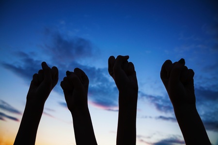 Four clenched fists raised against blue skyの写真素材