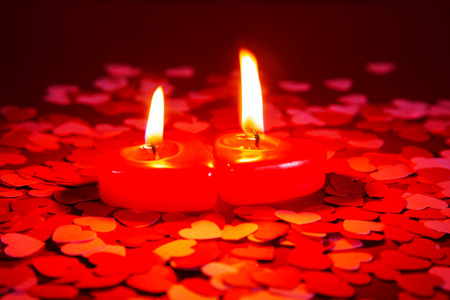 Two red burning candles against dark backgroundの写真素材