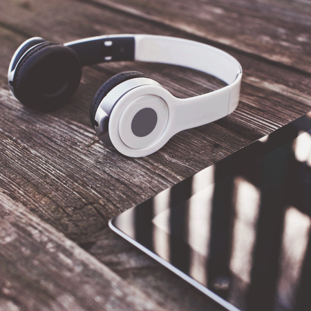 Tablet computer with headphones against wooden backgroundの写真素材