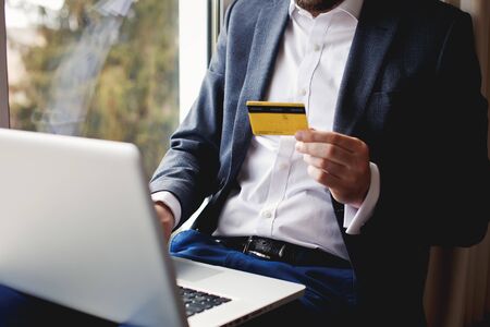 Men in suit holding credit card and using laptop. Online shopping.の写真素材