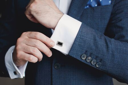 Close-up of a man in a tux fixing his cufflink.の写真素材