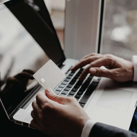 Men hand holding credit card and type payment information on keyboard.の写真素材