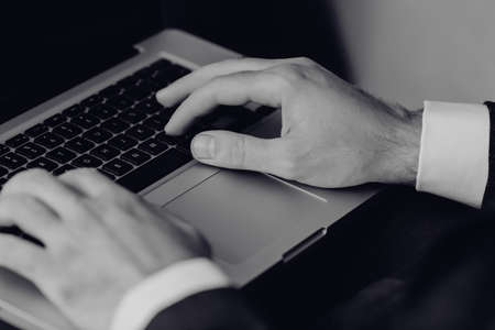 Businessman working on keyboard computer laptop man sitting on the table and using internet technology at workplace in office / Male hand typing on keyboard conceptの写真素材