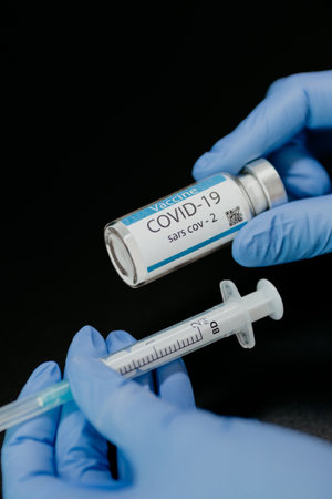 Doctor holding syringe and COVID-19 vaccine.