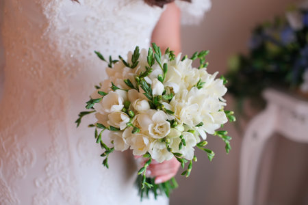 wedding bouquet of white freesia in the hands of the brideの写真素材