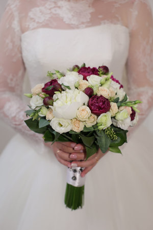 violet and white wedding bouquet of roses in the hands of the brideの写真素材