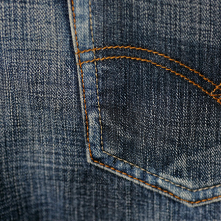 Denim texture or denim background with seam. Rough uneven edges.