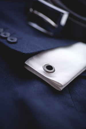 Close up of a cufflinks and belt on a blue suit.