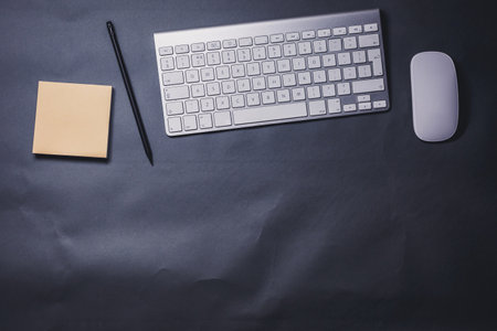 Office desk table with keyboard, mouse, notebook and pen. Top view with copy spaceの写真素材