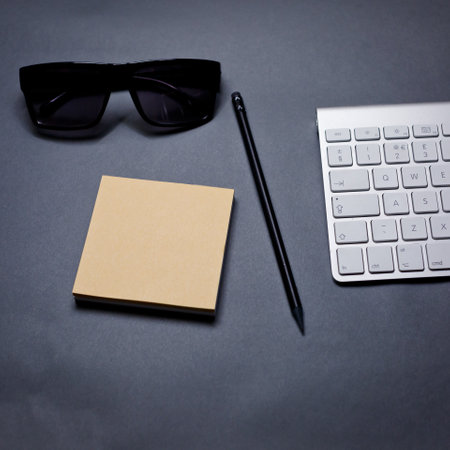 Keyboard, glasses, notebook and pencil on a gray background.の写真素材