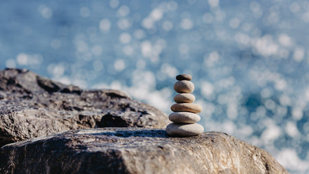 Stack of zen stones on a rock with sea in the backgroundの写真素材