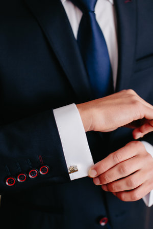 groom buttoning cufflinks on the sleeve of his wedding suit