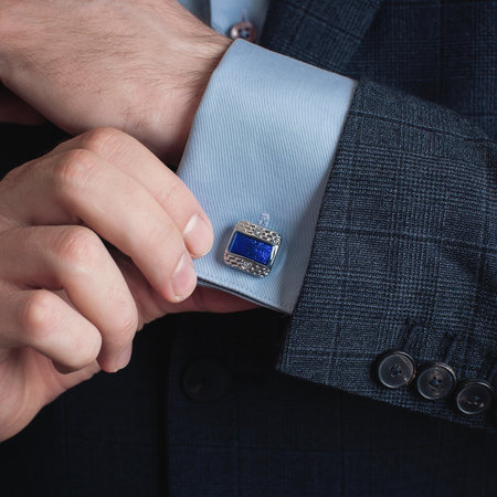 Close up of a man's hand adjusting a cufflink on a blue suitの写真素材