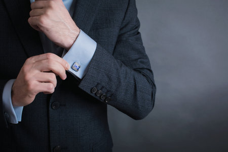 Close-up of a businessman adjusting his tie on a gray backgroundの写真素材