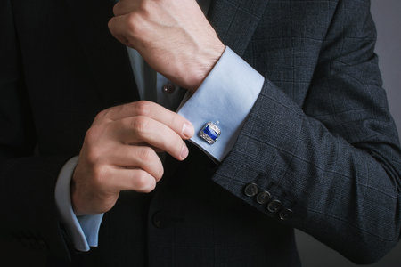 Close-up of a man buttoning his business suit with a blue cardの写真素材