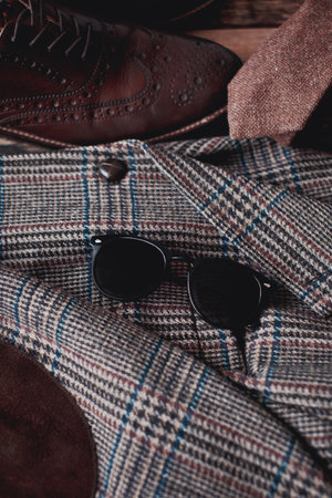 Fashionable men's clothing. Brown checkered plaid, brown shoes and sunglasses on wooden background.の写真素材