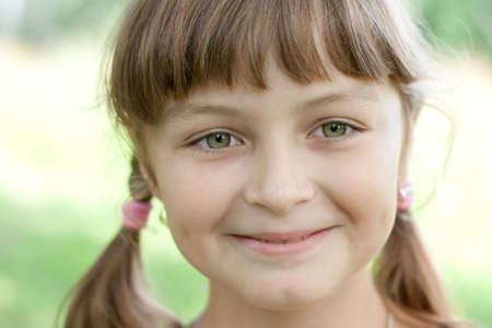 Fullface portrait of smiling little girl with green eyes and blond hairの写真素材