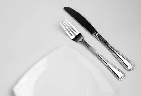 Place setting for one person. Knife, square white plate and fork.の写真素材