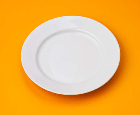White round plate on orange backgroundの写真素材