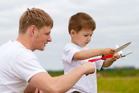 Father and son have fun with toy aircraft model in parkの写真素材