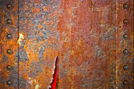 Torn rusty metal texture with rivets over red background