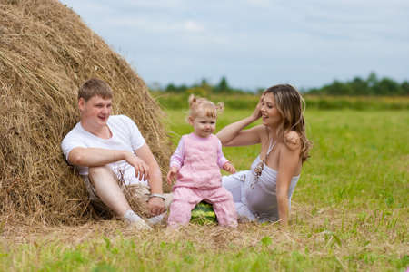 Happy family in haystack or hayrick with watermelonの写真素材